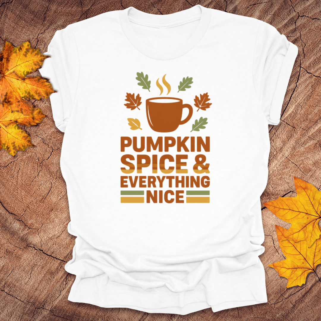 White t-shirt with 'Pumpkin Spice & Everything Nice' design on a wooden surface with fall leaves.