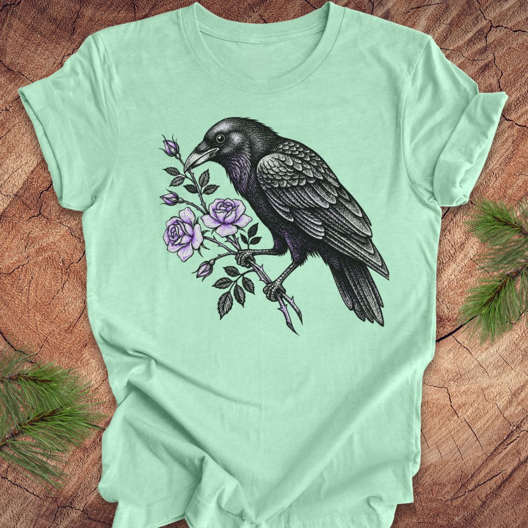 Mint green t-shirt with a raven and floral design on a wooden surface