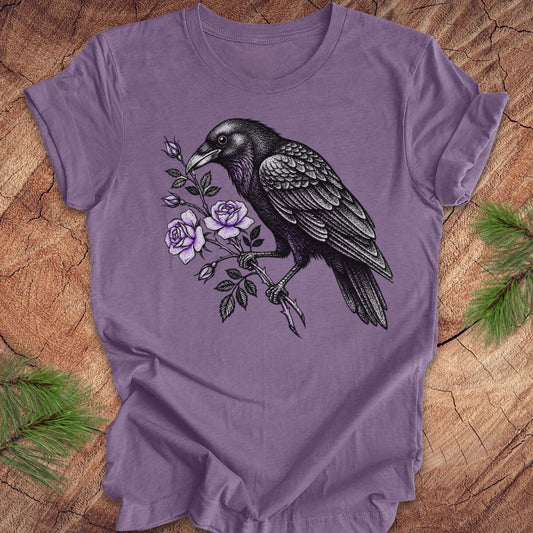 Purple t-shirt with a raven and floral design on a wooden surface