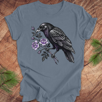 Blue t-shirt with a raven and floral design on a wooden surface