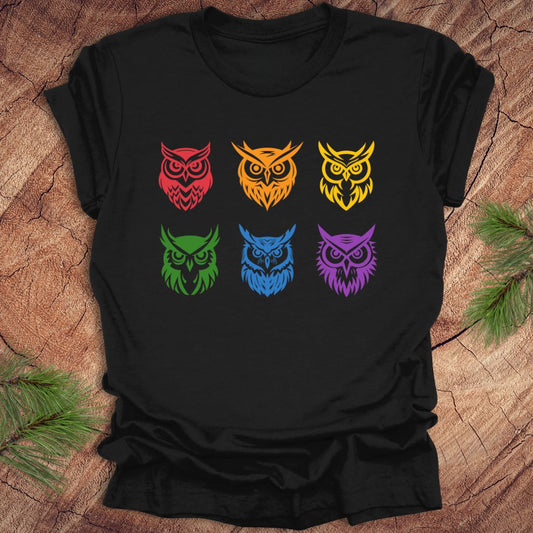 Black t-shirt with 6 rainbow colored owl designs on a wooden surface