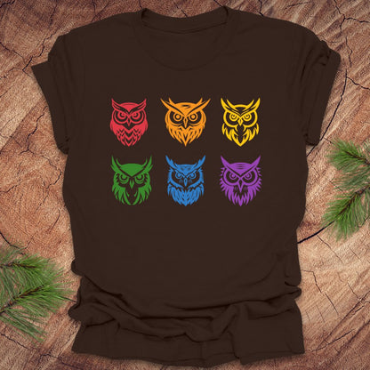 Brown t-shirt with 6 rainbow colored owl designs on a wooden surface