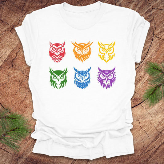 White t-shirt with 6 rainbow colored owl designs on a wooden surface