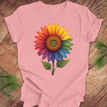 Pink t-shirt with a colorful sunflower graphic on a wooden surface.