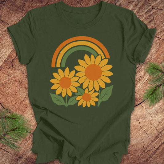 Green t-shirt with a rainbow and sunflower design on a wooden surface