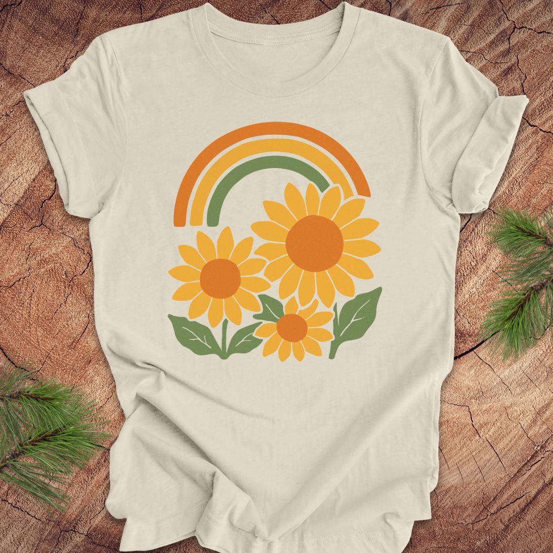 Beige t-shirt with sunflower and rainbow design on a wooden surface