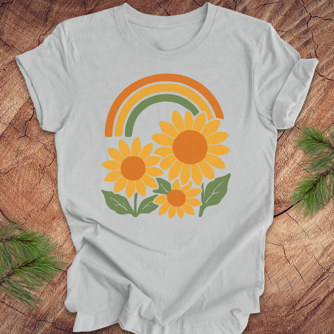Gray t-shirt with a rainbow and sunflower design on a wooden surface