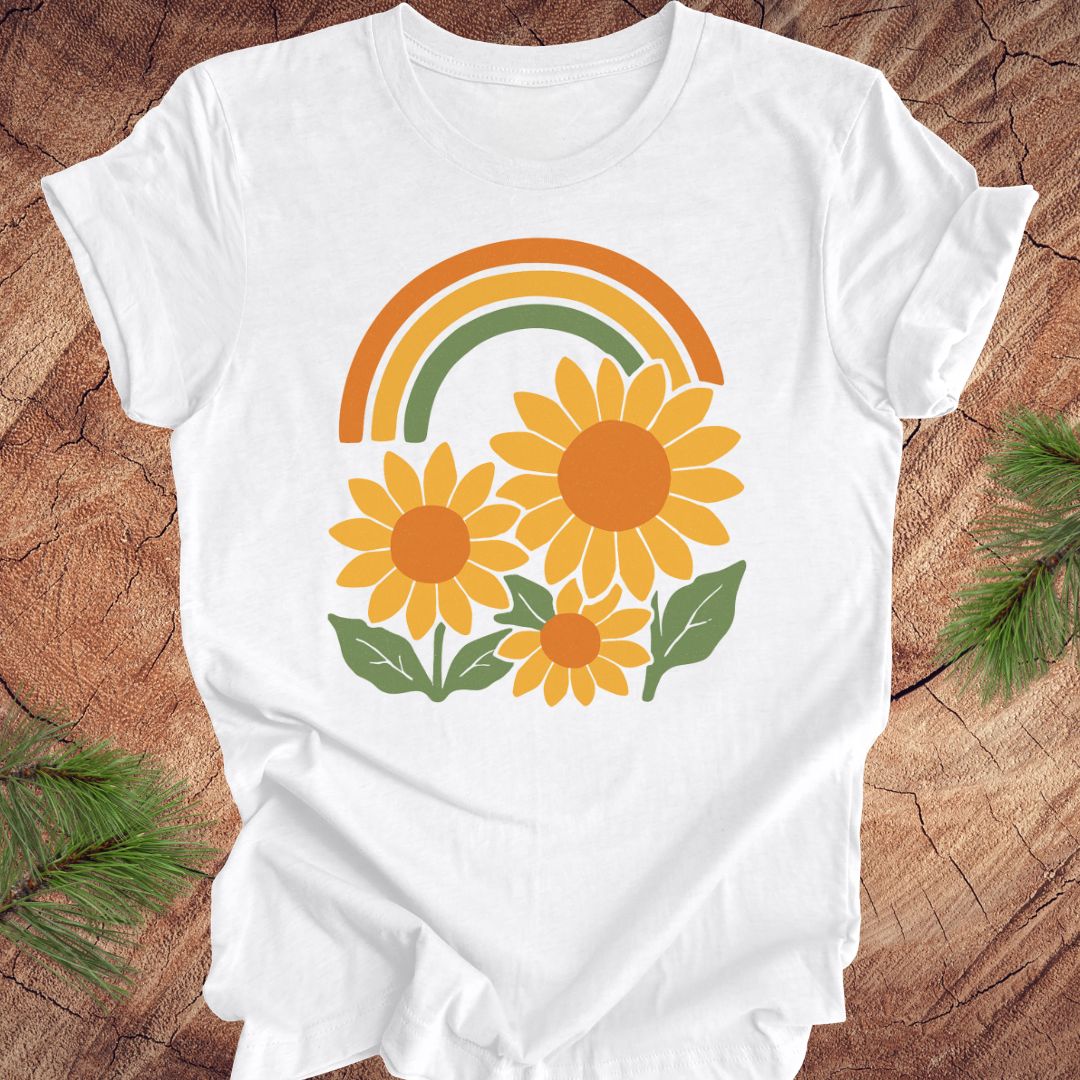 White t-shirt with sunflower and rainbow design on a wooden surface
