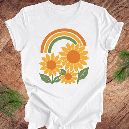 White t-shirt with sunflower and rainbow design on a wooden surface