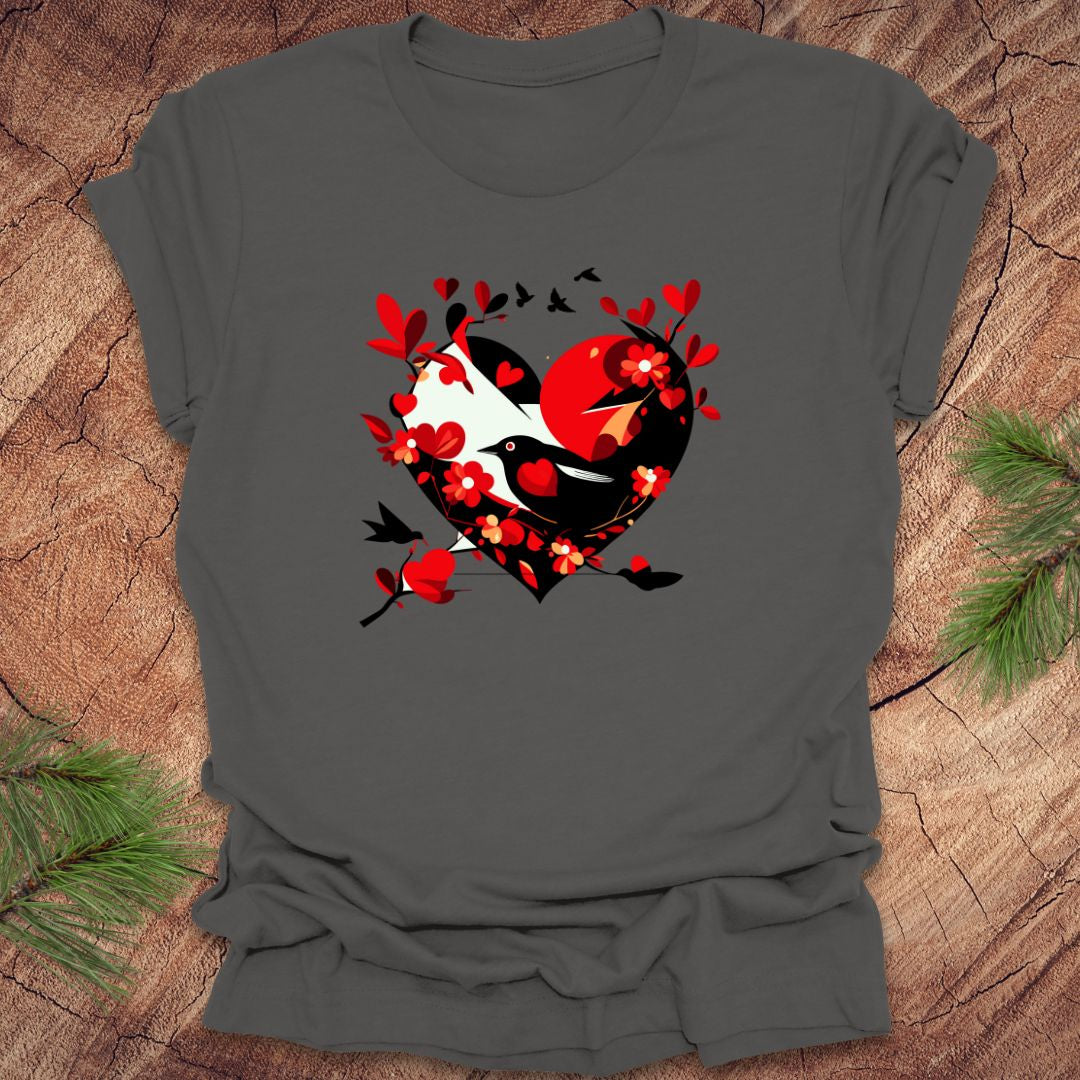 Dark gray t-shirt with a red and black heart with a raven inside of it, with red hearts flying off of it, on a wooden background.