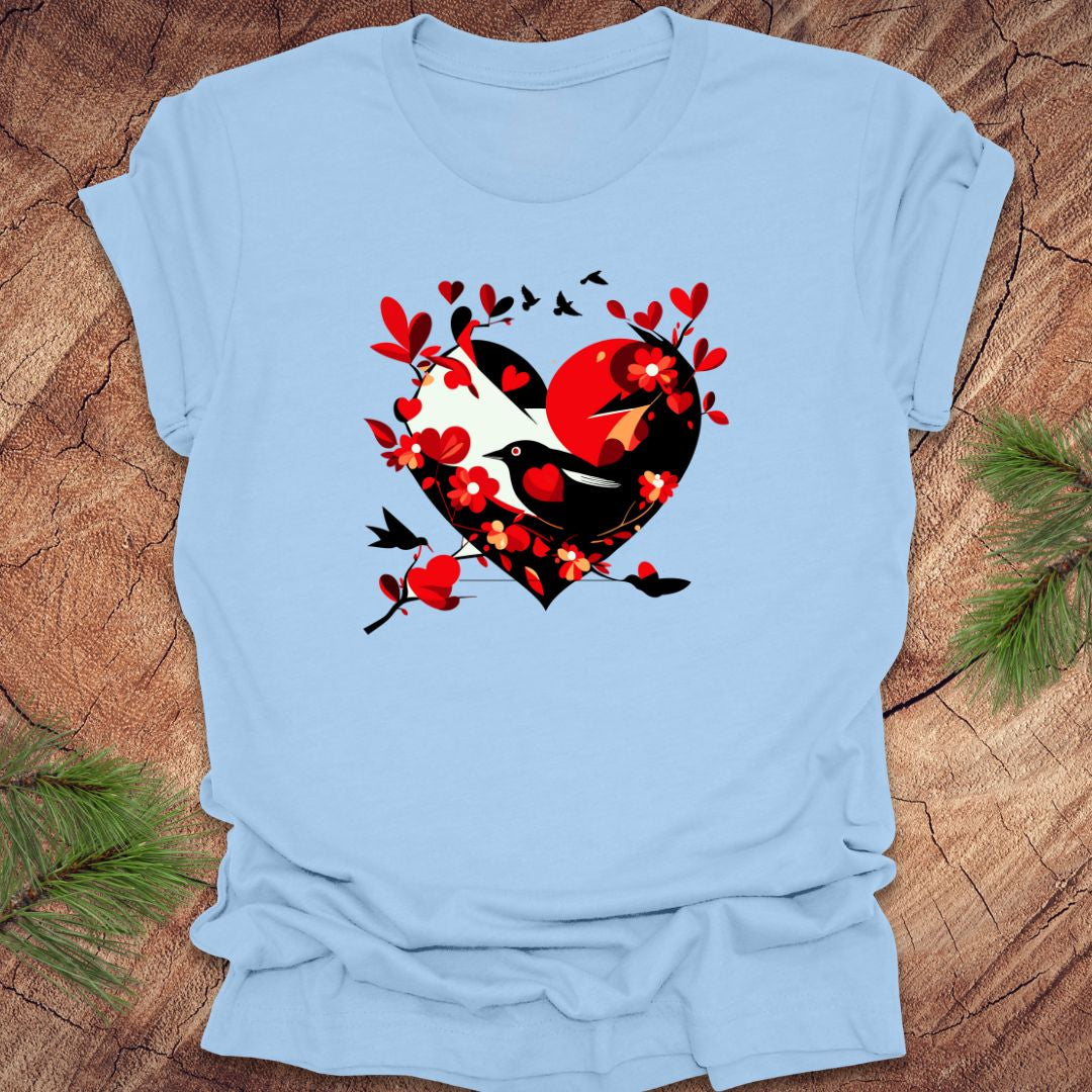 Baby blue t-shirt with a red and black heart with a raven inside of it, with red hearts flying off of it, on a wooden background.