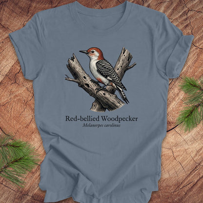 Blue t-shirt with a red-bellied woodpecker graphic and text on a wooden surface.