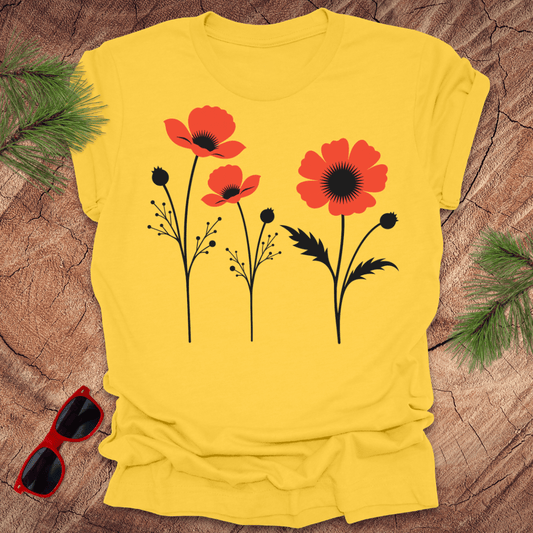 Yellow t-shirt with red and black floral design on a wooden surface with sunglasses and greenery.