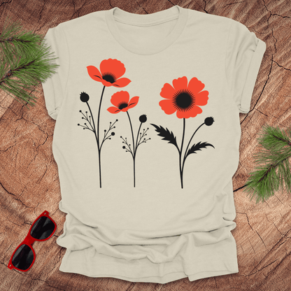 Beige t-shirt with red floral design on a wooden surface with sunglasses and greenery.
