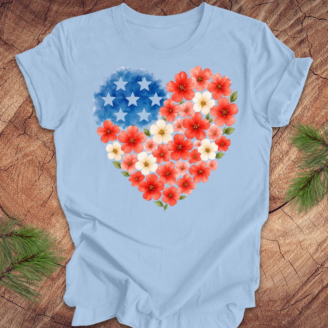 Light blue t-shirt with a heart design of red, white, and blue flowers on a wooden surface.