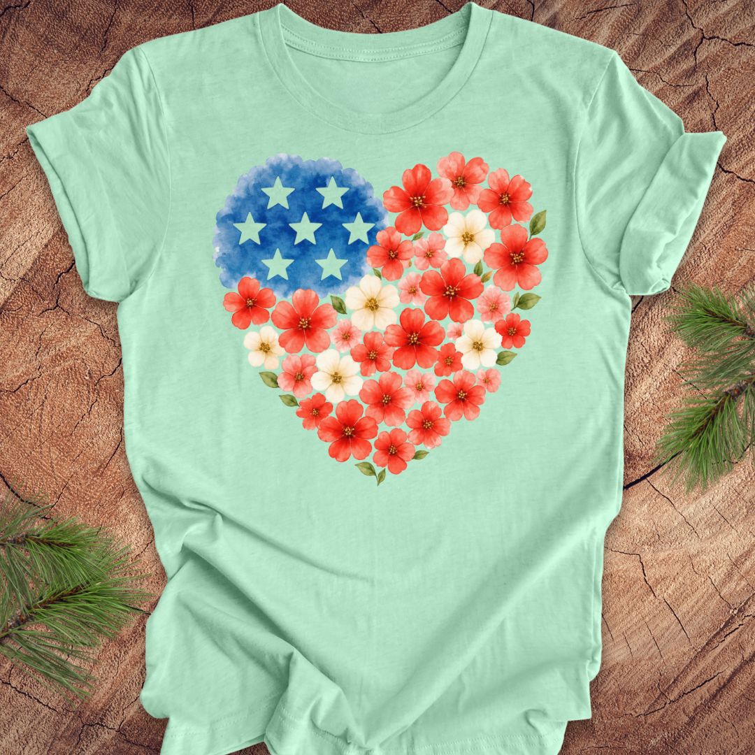 Mint green t-shirt with a heart design of flowers and stars on a wooden surface.