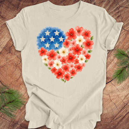 Beige t-shirt with a heart design featuring red flowers and a blue section with white stars on a wooden surface.