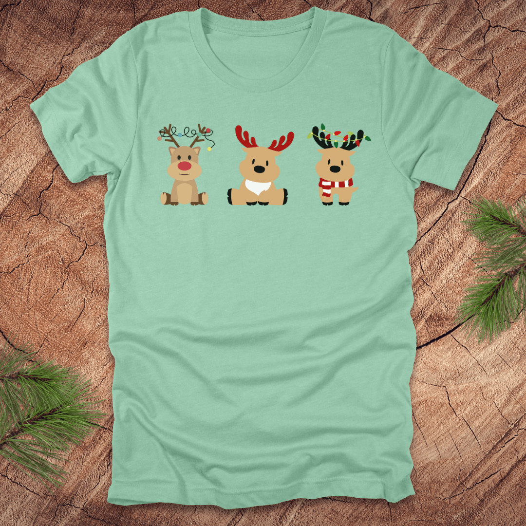 Light green t-shirt with cartoon reindeer design on a wooden surface