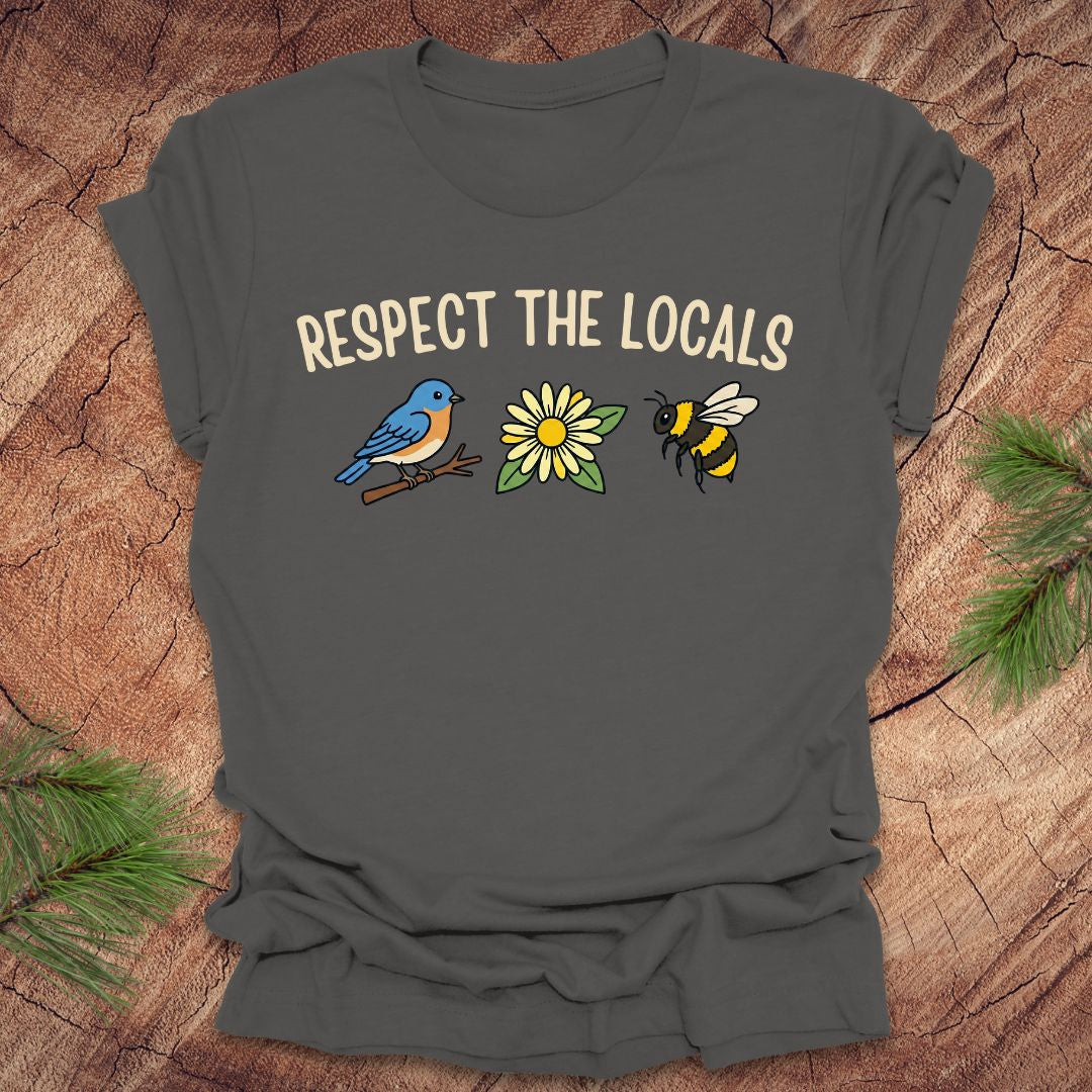 Gray t-shirt with 'Respect the Locals' text and bird, flower and bee graphics on a wooden surface