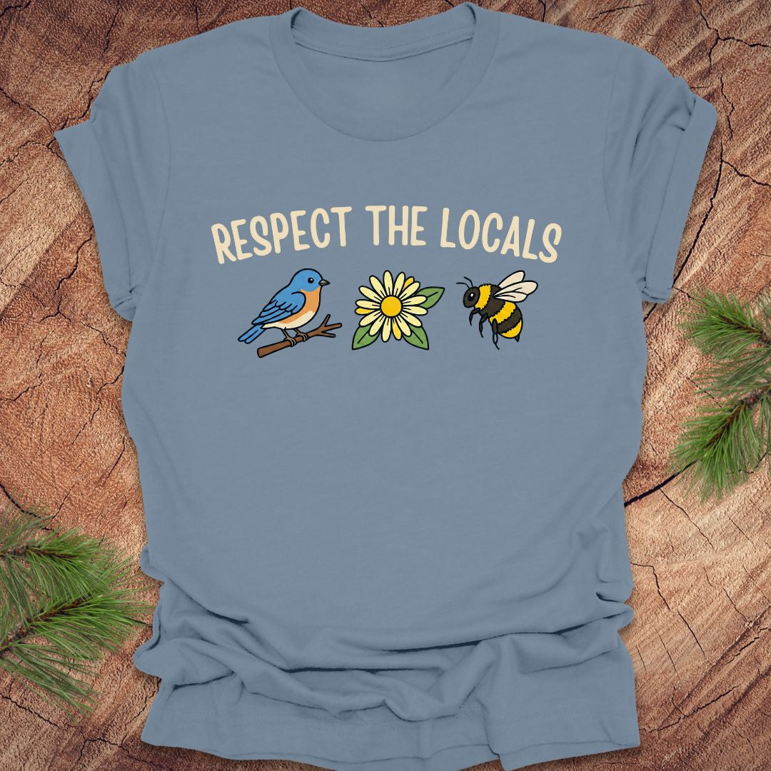 Steel blue t-shirt with 'Respect the Locals' text and bird, flower and bee graphics on a wooden surface