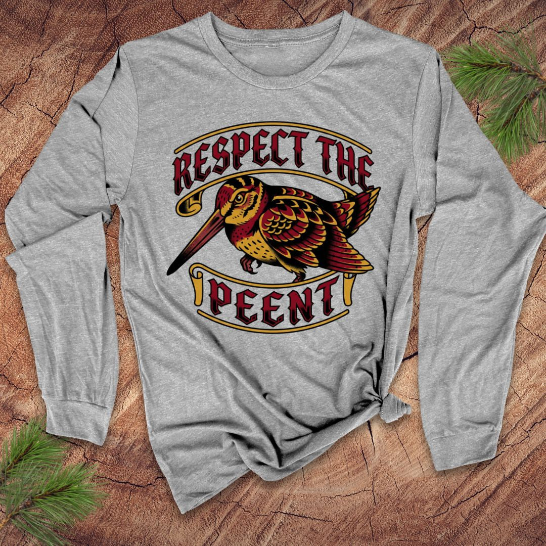 Gray long-sleeve shirt with a colorful graphic of a woodcock and text 'Respect the Peent' on a wooden surface.