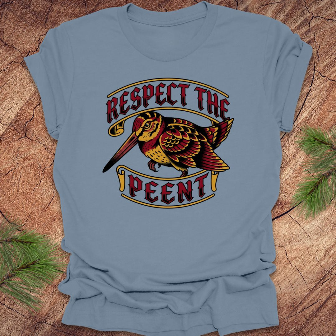 Blue t-shirt with a colorful graphic of a bird and text 'Respect the Peent' on a wooden surface.