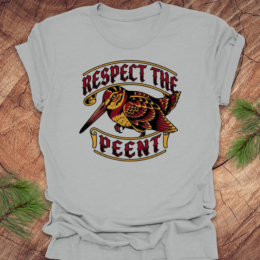Gray t-shirt with a graphic design of a bird and text 'Respect the Peent' on a wooden surface.