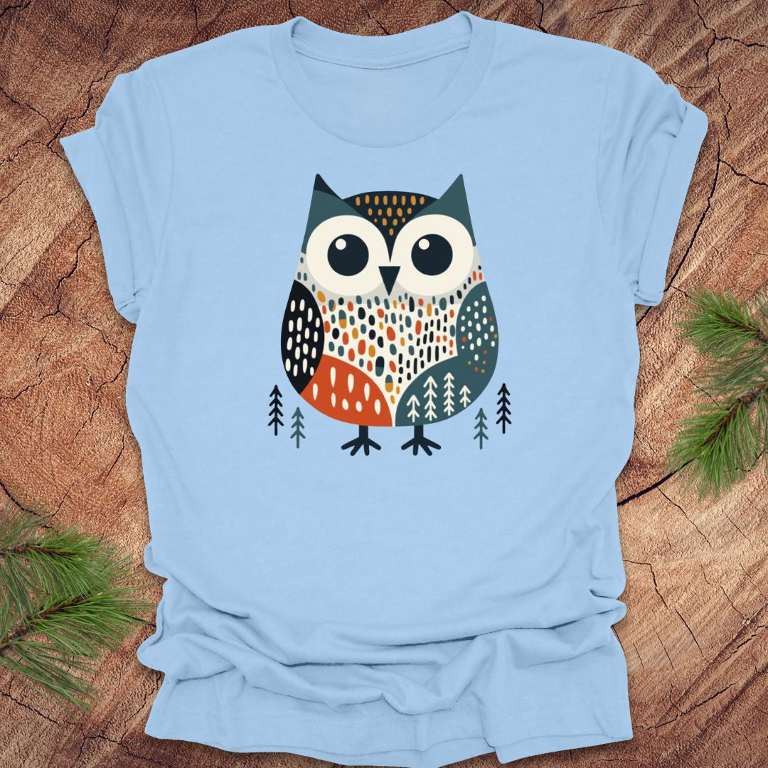 Light blue t-shirt with a colorful owl design on a wooden surface.