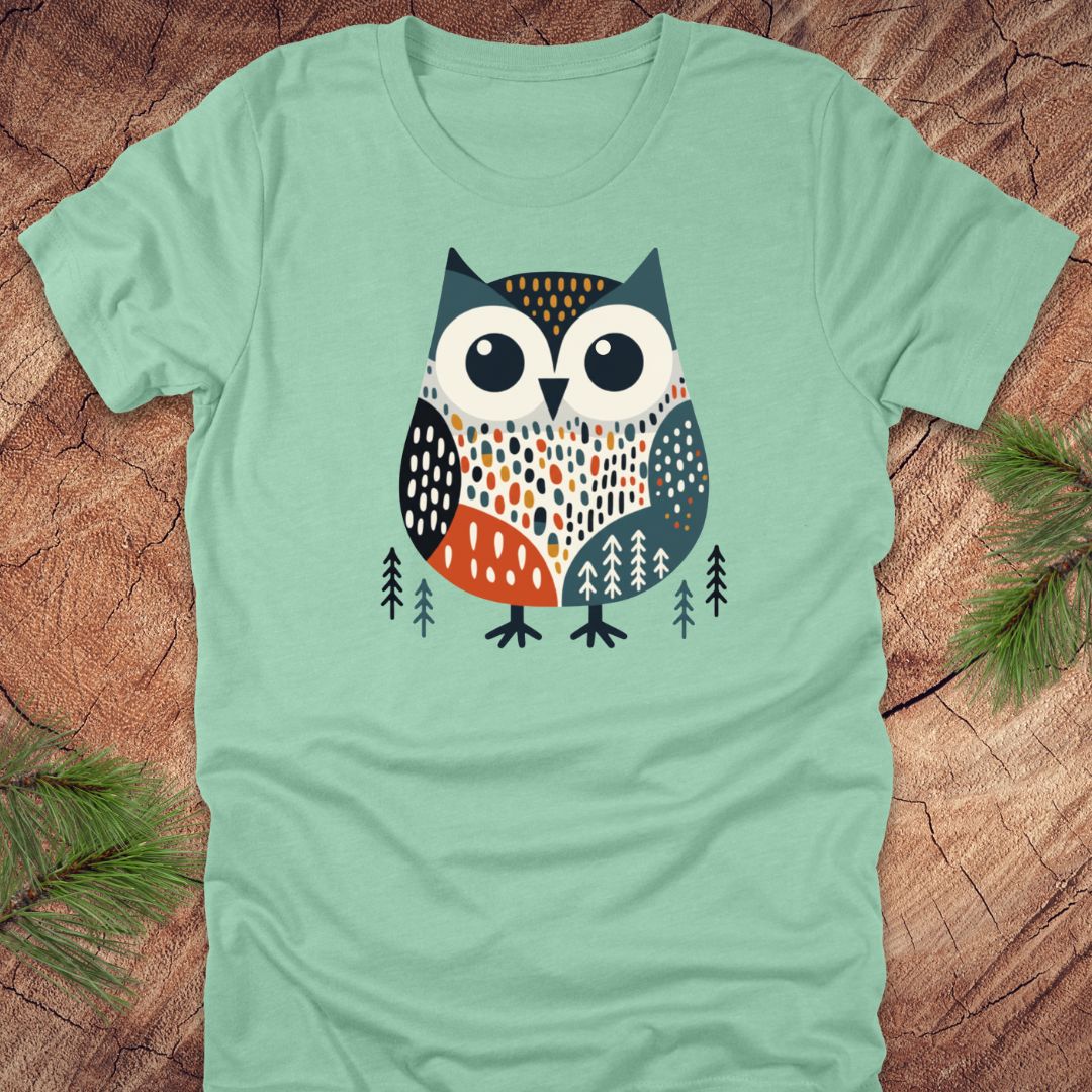 Light green t-shirt with a colorful owl design on a wooden surface
