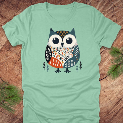 Light green t-shirt with a colorful owl design on a wooden surface