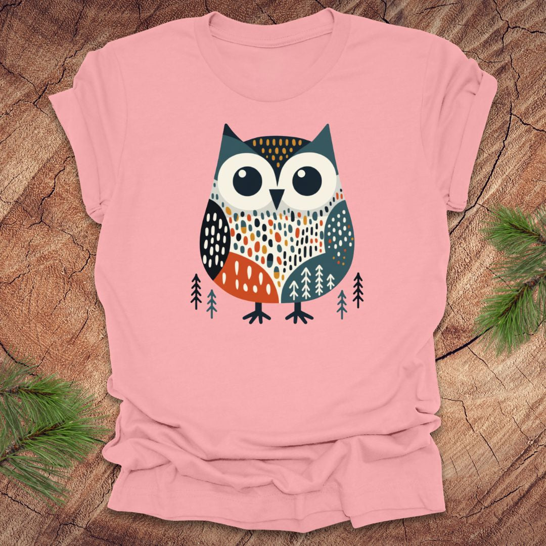 Pink t-shirt with a colorful owl design on a wooden surface