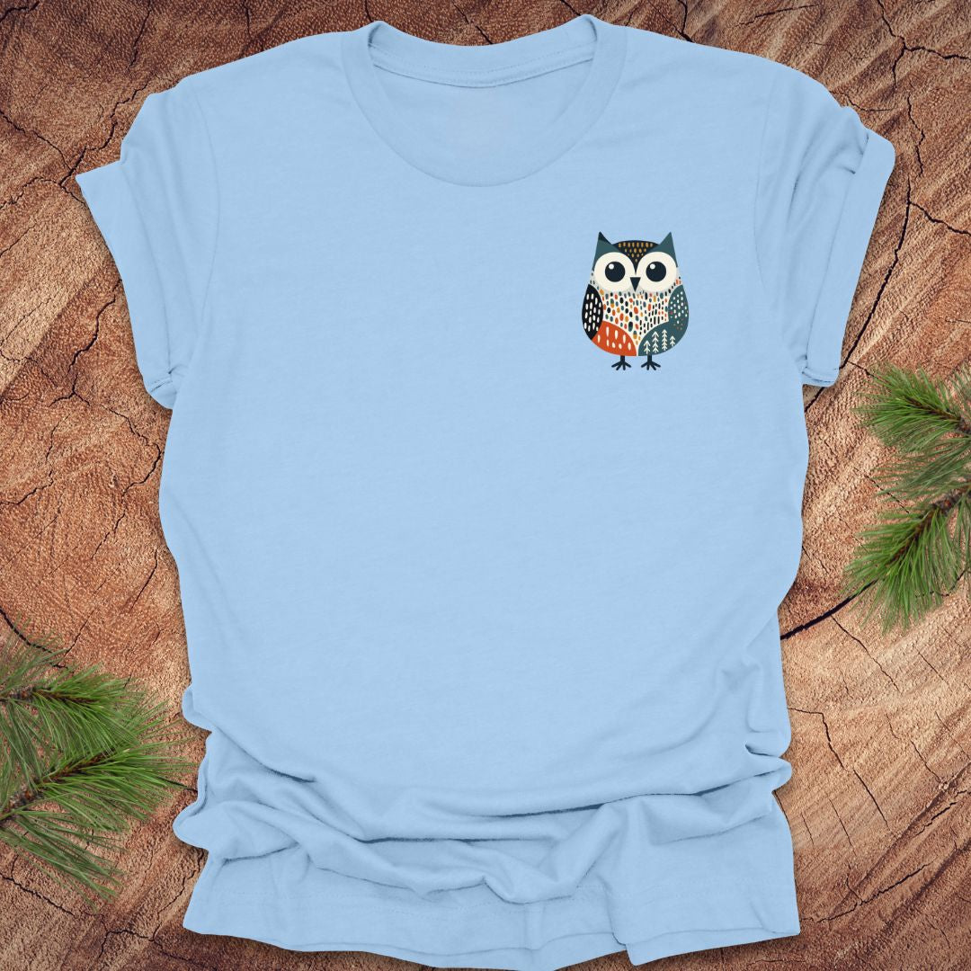 Light blue t-shirt with a pocket owl design on a wooden surface