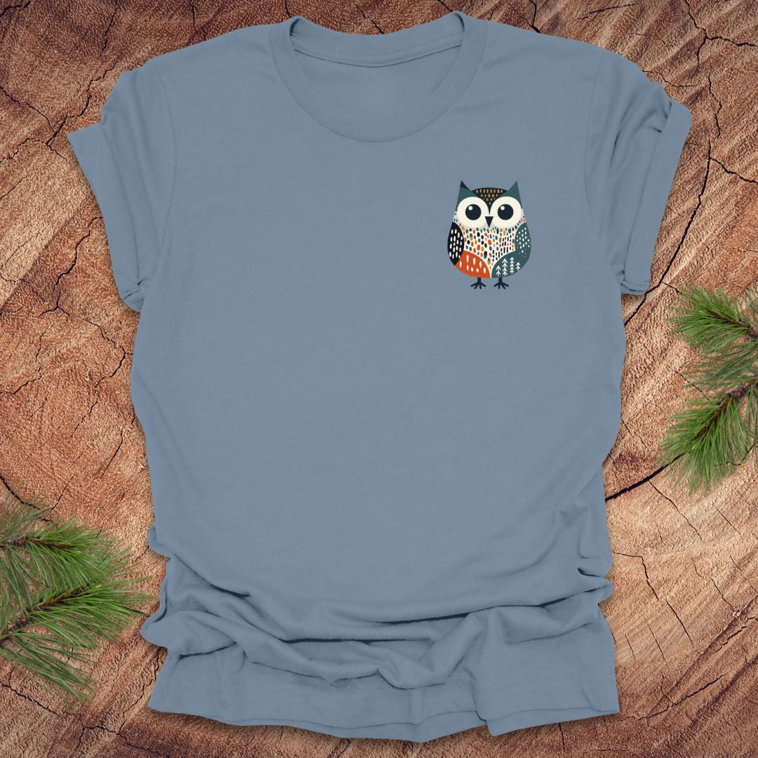 Blue t-shirt with a pocket owl design on a wooden surface