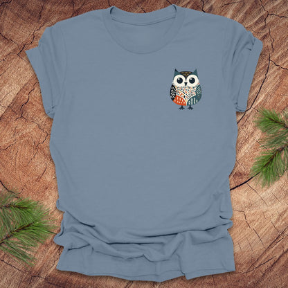 Blue t-shirt with a pocket owl design on a wooden surface