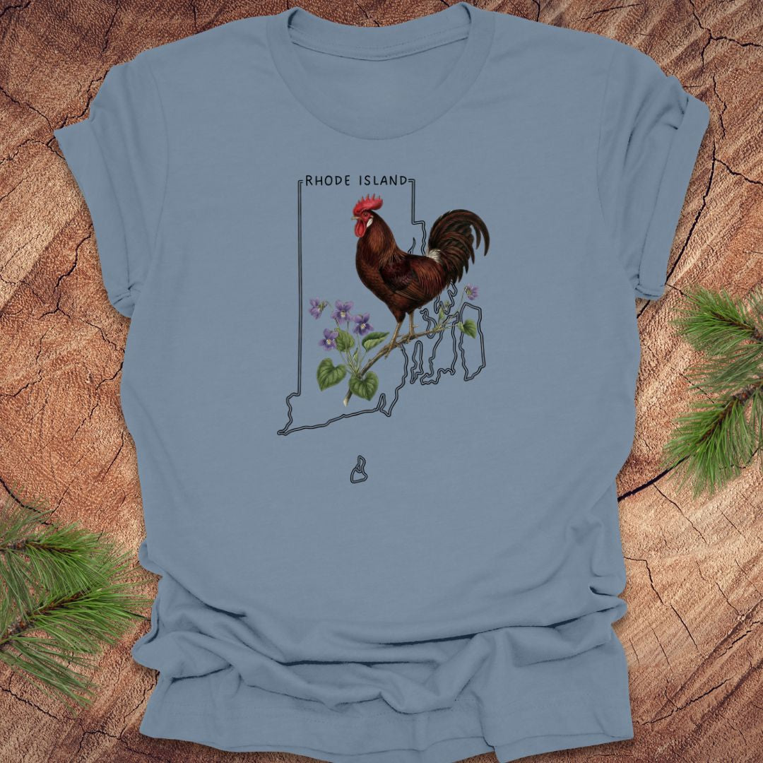 Steel blue t-shirt with the state outline of Rhode Island with state bird, red rooster and flower, violet,  on a wooden surface