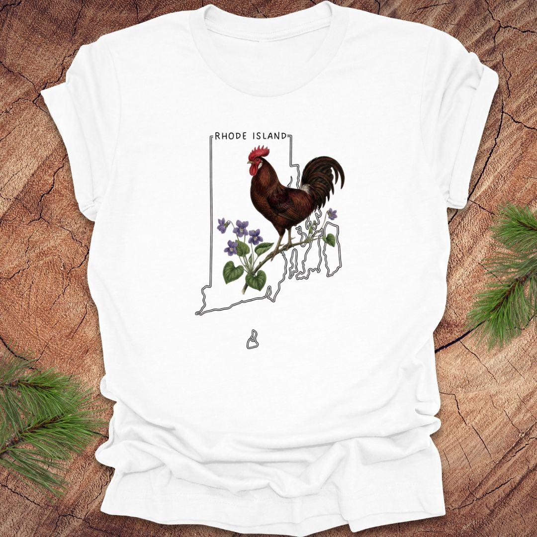 White t-shirt with the state outline of Rhode Island with state bird, red rooster and flower, violet,  on a wooden surface