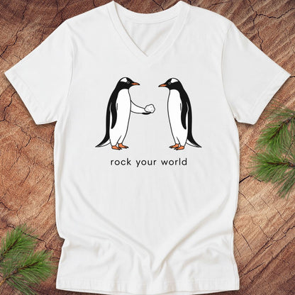 White v-neck t-shirt with two penguins and text, 'rock your world' on a wood background.