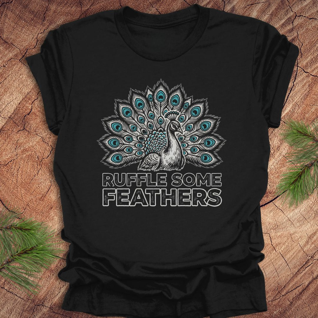 Black t-shirt with peacock design and 'Ruffle Some Feathers' text on a wooden surface.