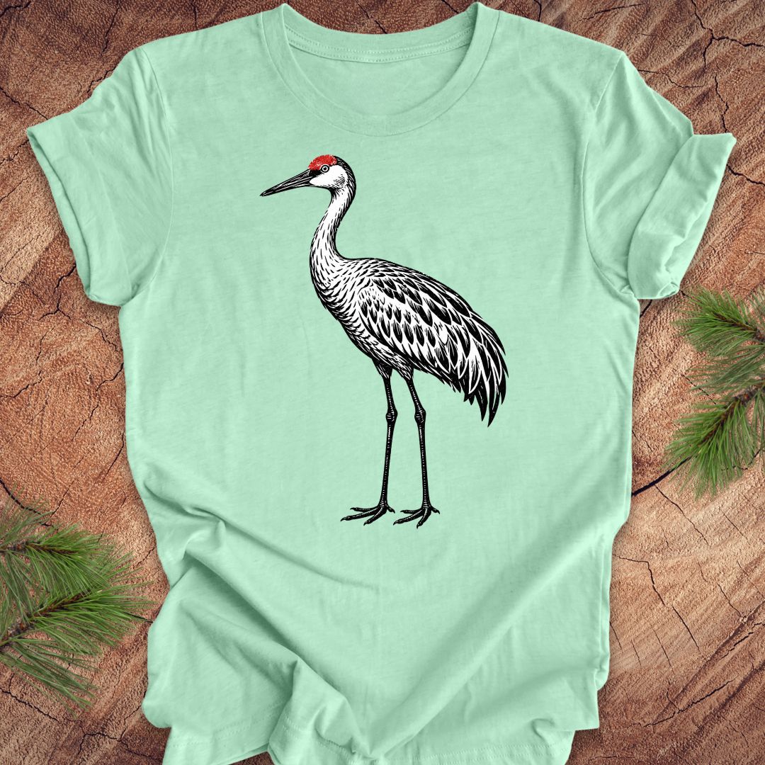 Green t-shirt with a woodcut sandhill crane bird on a wood background.