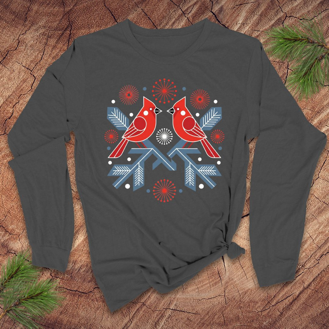 Light gray long-sleeve shirt with red cardinals and blue snowflakes on a wooden surface.