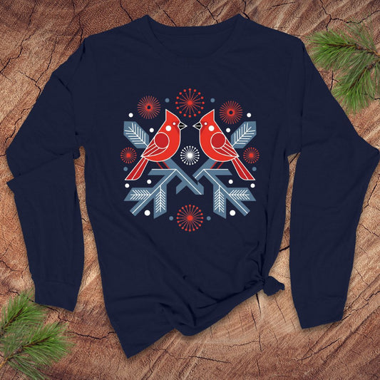 Navy blue long-sleeve shirt with red cardinal design on a wooden surface with pine branches.