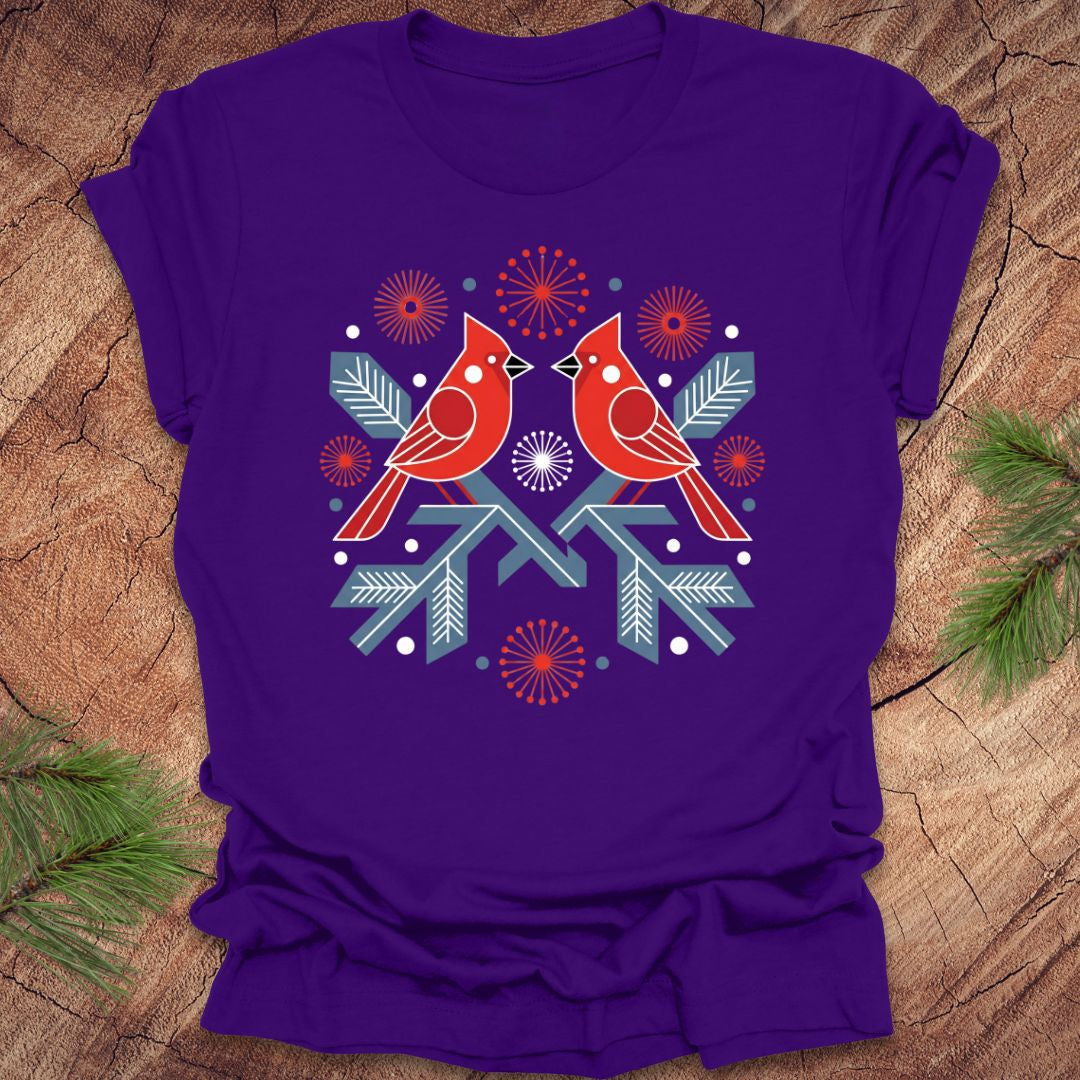 Purple t-shirt with a folk art red cardinal birds design on a wooden surface