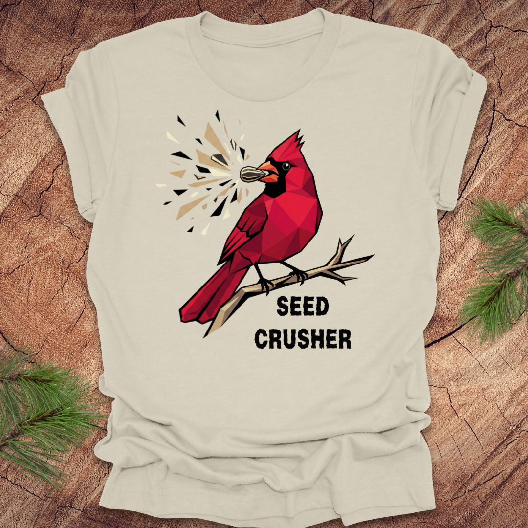 Beige t-shirt with a red cardinal graphic and 'Seed Crusher' text on a wooden surface.