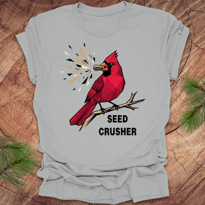 Gray t-shirt with a red cardinal graphic and 'Seed Crusher' text on a wooden surface.