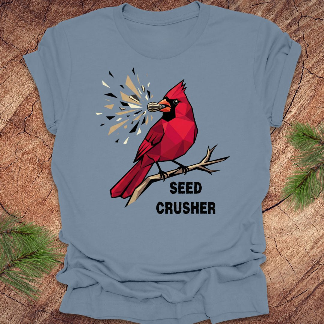 Blue t-shirt with a red cardinal graphic and 'Seed Crusher' text on a wooden surface.