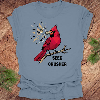 Blue t-shirt with a red cardinal graphic and 'Seed Crusher' text on a wooden surface.