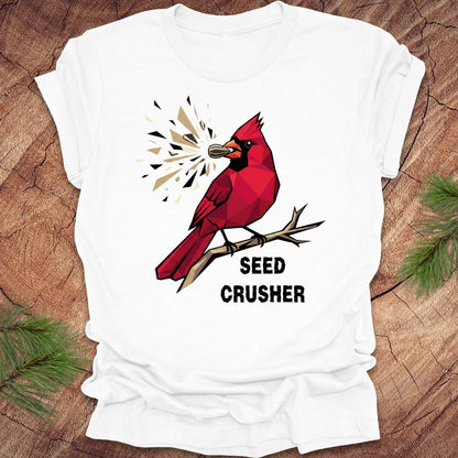 White t-shirt with a red cardinal graphic and 'Seed Crusher' text on a wooden surface.