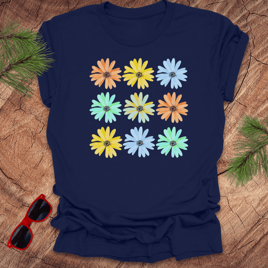 Navy blue t-shirt with colorful flower pattern on a wooden surface with sunglasses and greenery.