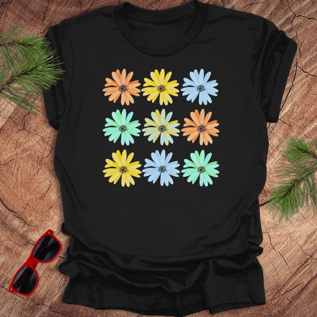 Black t-shirt with colorful flower pattern on a wooden surface with sunglasses.