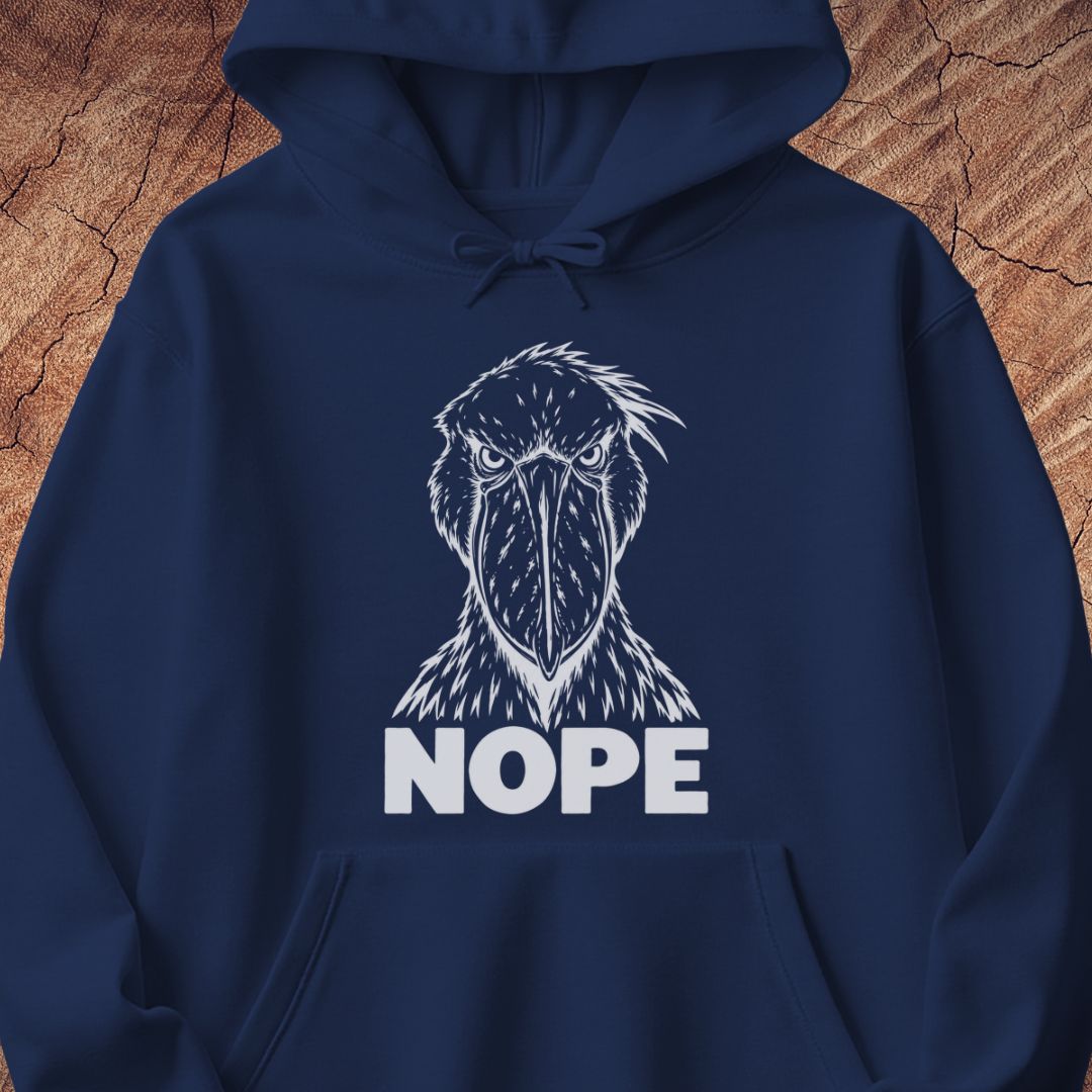 Navy hoodie with a white line-art Shoebill staring straight ahead above the word NOPE, laid flat on a rustic wood background.